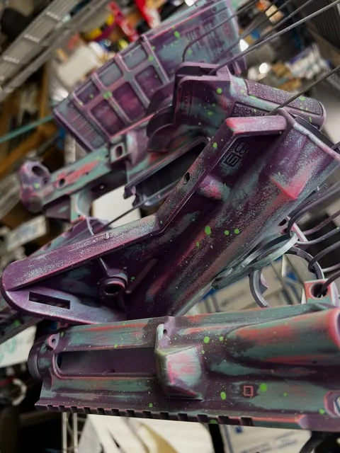 Purple, green, and pink splatter Cerakote applied across matching rifle components.