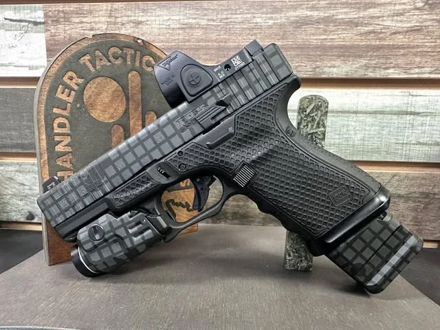 A patterned pistol with a fitted Trijicon optic and matching light.