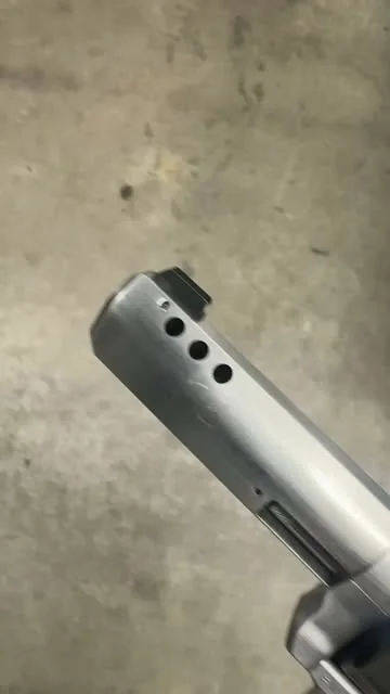 Close view of three machined ports at the front of a pistol slide.