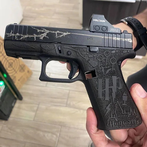 A black pistol with detailed laser engraving across the slide and grip.