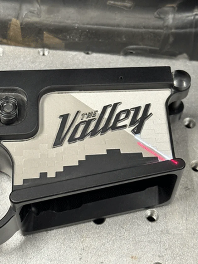 A firearm component held in a machining fixture under a guide light.